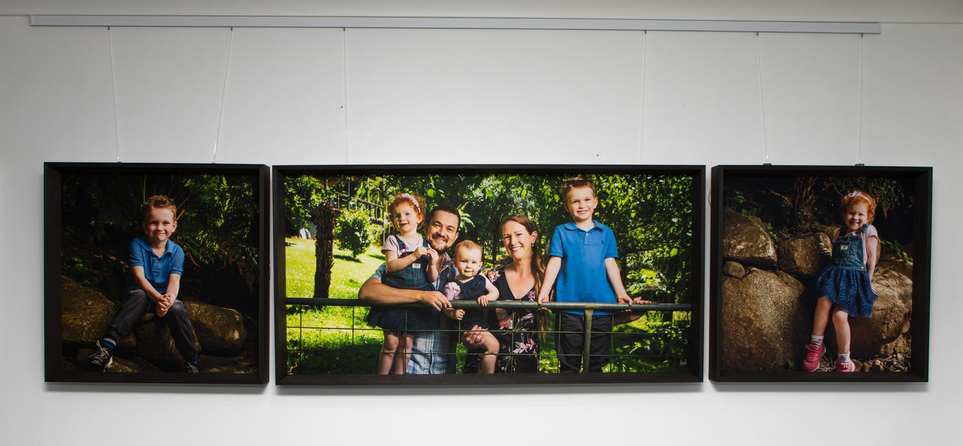 A triptych of premium canvas family portraits displayed together on a loungeroom wall