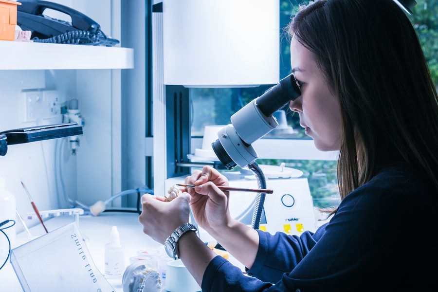 A woman at a microscope, focused on her work, in a genuine work environment