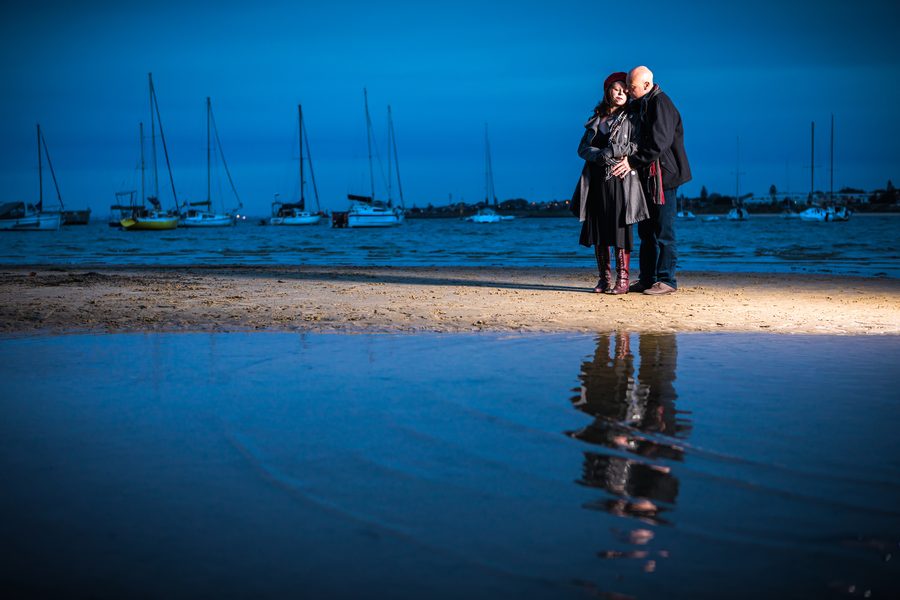 A couple on the beach with their reflection in a shallow pool