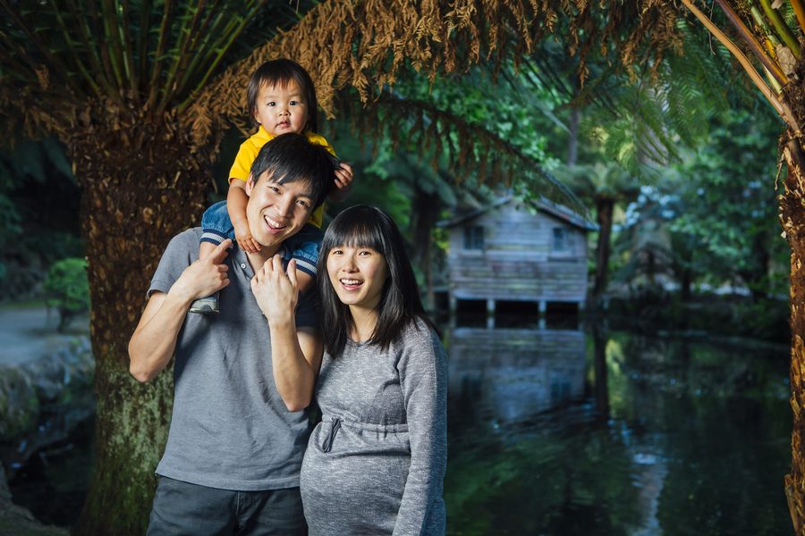 A family of three walking beneath a golden hanging foliage archway