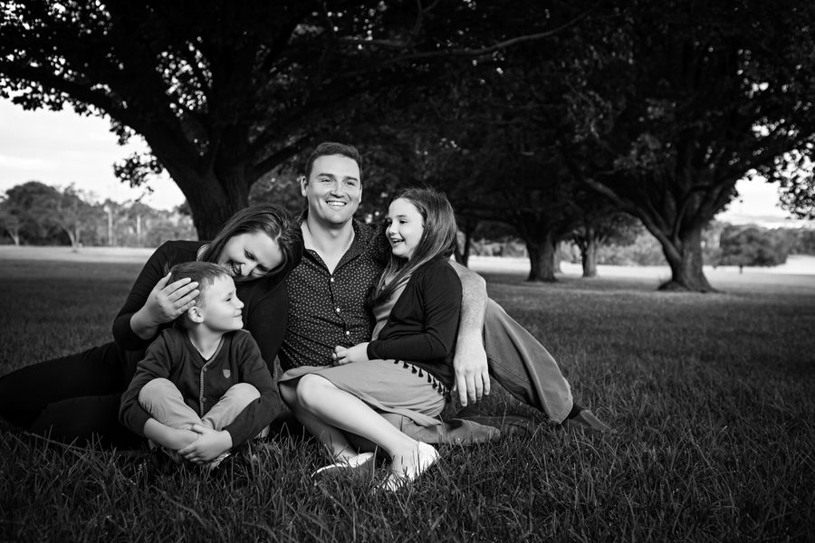 A family of four nestled together beneath a massive tree trunk