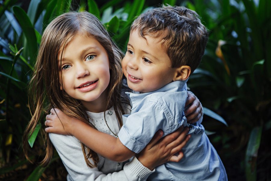 Two siblings together in a garden, warm natural colour