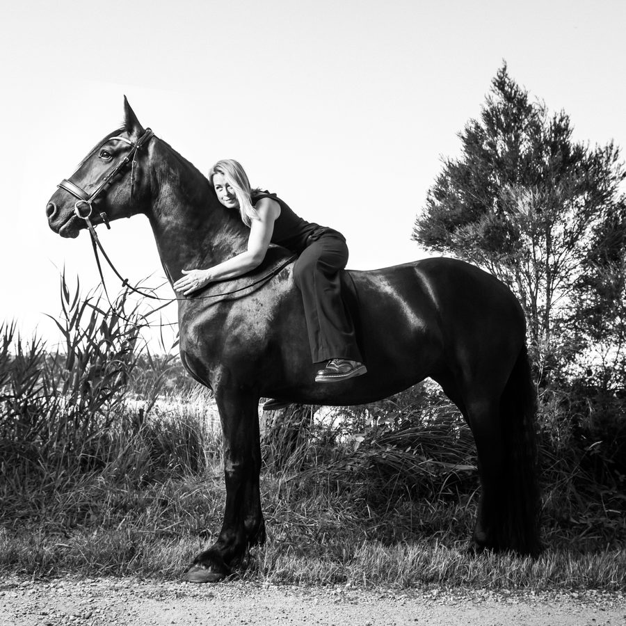 Woman on a black horse in a rural field, fine art black and white portrait