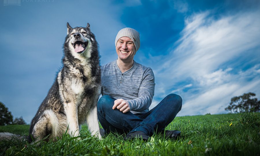 Man with a joyful husky outdoors against a vibrant blue sky