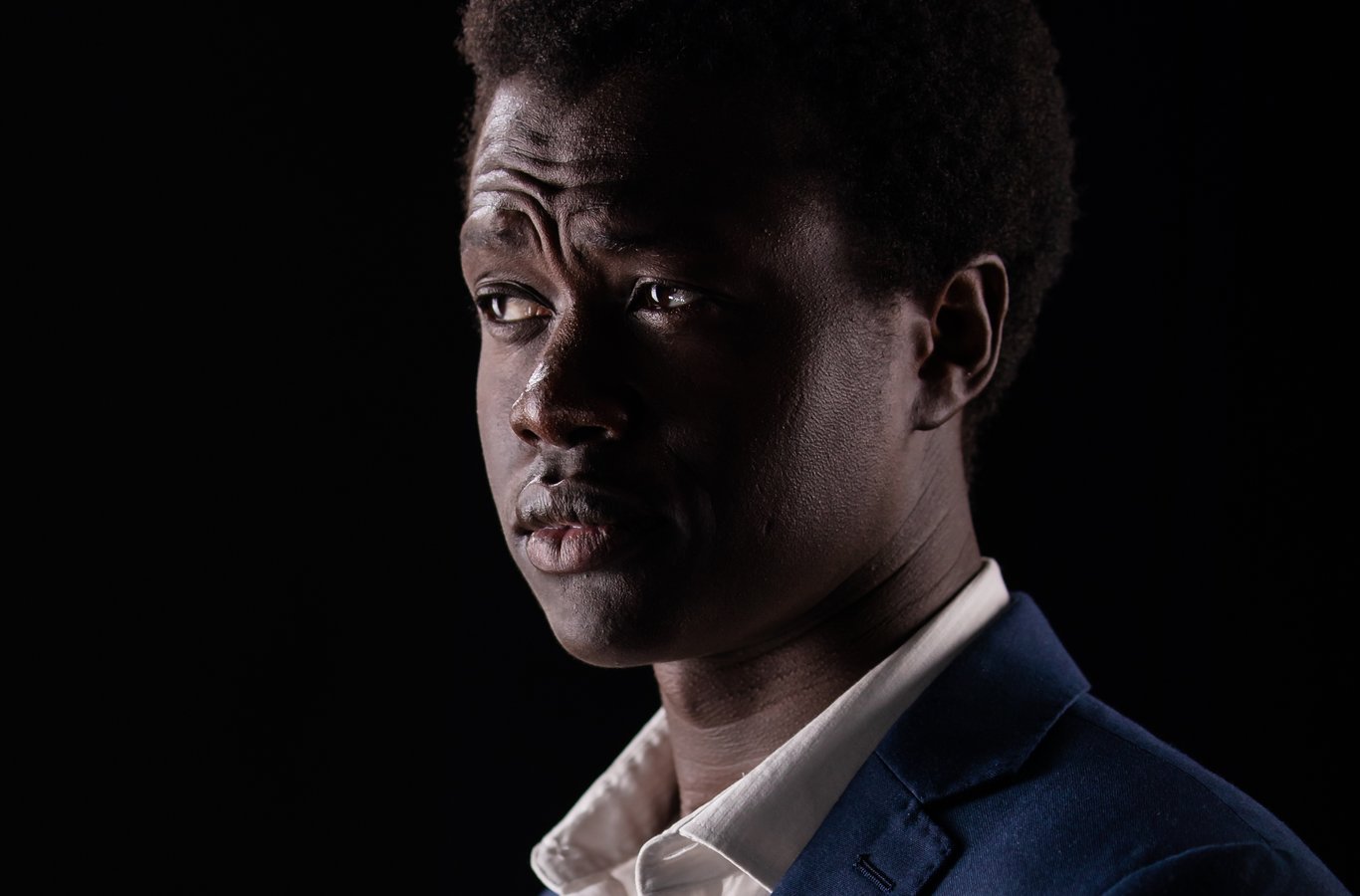 Studio headshot, individual, three-quarter pose, navy blazer, white shirt