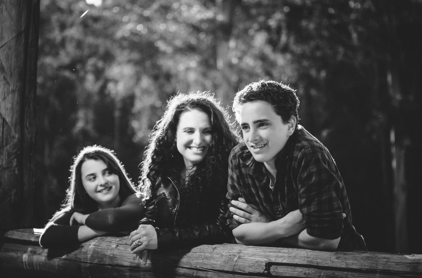 Three people in black and white portrait with excellent backlighting creating distinctive rim lighting effect on hair and shoulders